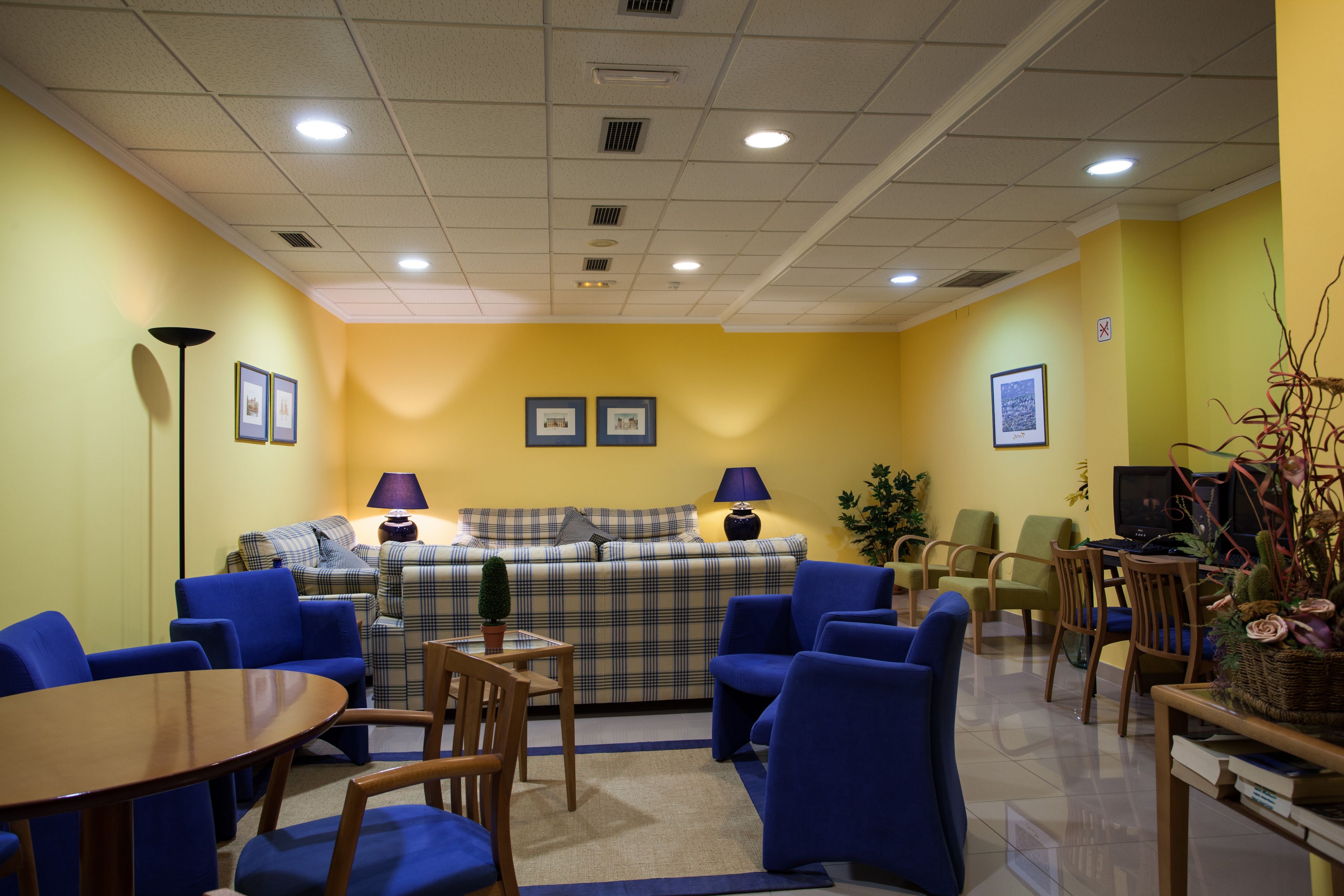 A room with a sofa set, blue armchairs, a wooden table, and a television.