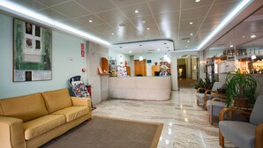 Un hall de hotel con mostrador de recepción, un sofá y una estación de café.