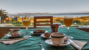 Una mesa servida con alimentos y bebidas para el desayuno, con vistas a un paisaje costero.