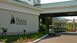 A building with a sign reading "Mainsail Conference Center" and a covered entrance. - Mainsail Suites (Tampa)