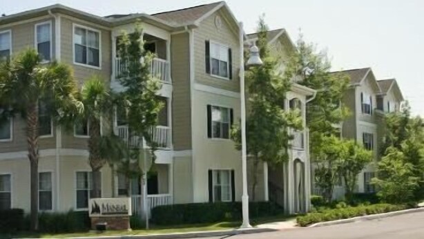 A multi-story residential building with a beige exterior, balconies, and a sign indicating it is a hotel. - Mainsail Suites (Tampa)