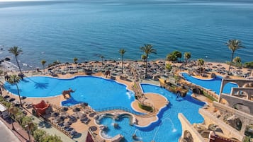 Una piscina techada, una piscina al aire libre, sombrillas