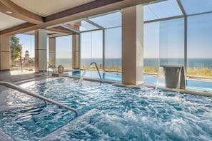A hot tub with a view of the ocean, surrounded by glass walls and columns. - Holiday World Riwo, Affiliated by Meliá (Benalmádena)