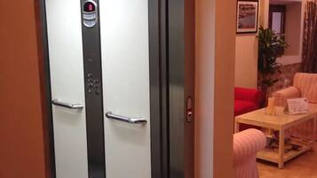 Un ascensor con pantalla digital, un agarradera metálica y una puerta con manija.