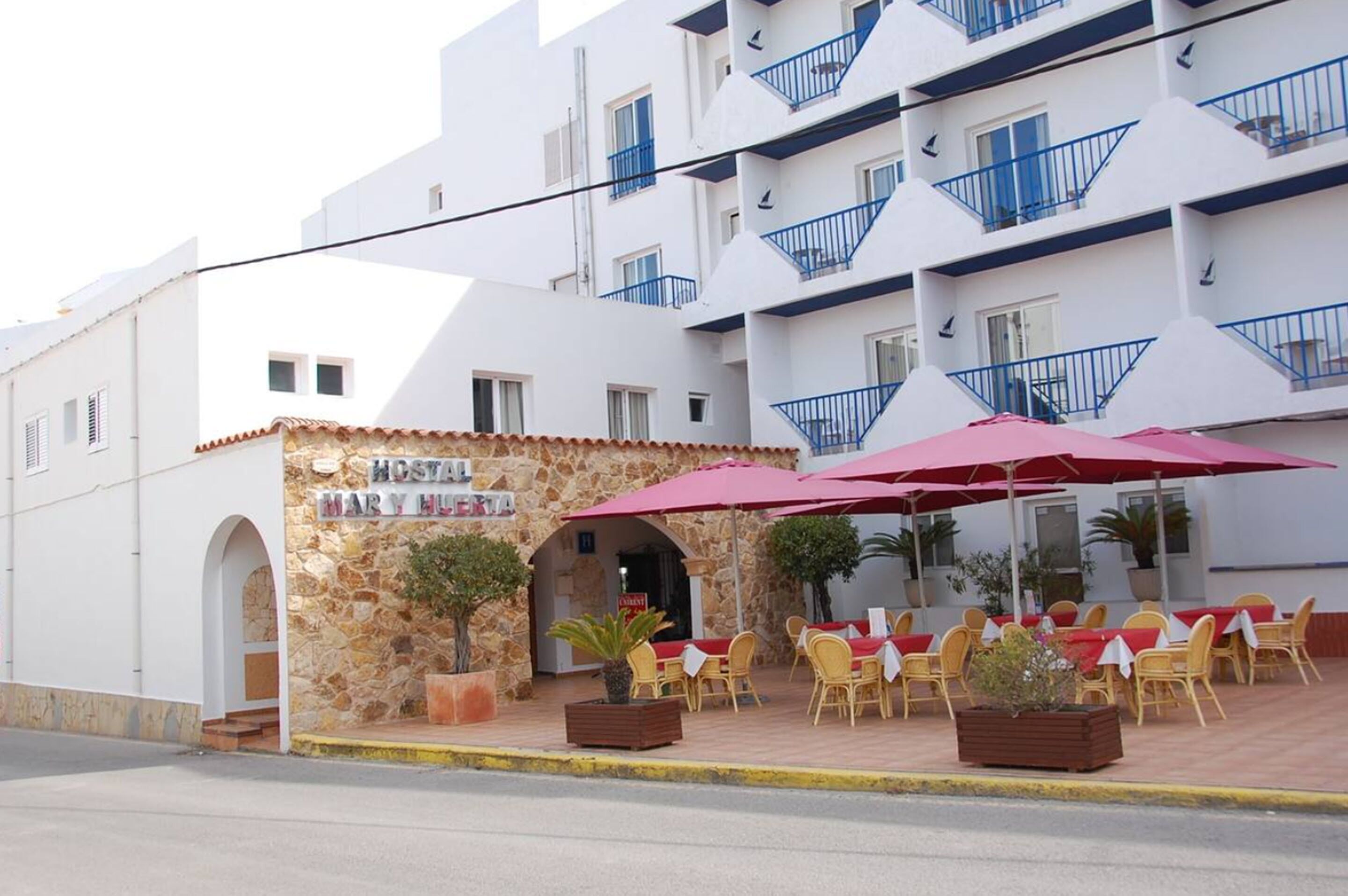 A hotel with outdoor seating, stone facade, and blue balconies.