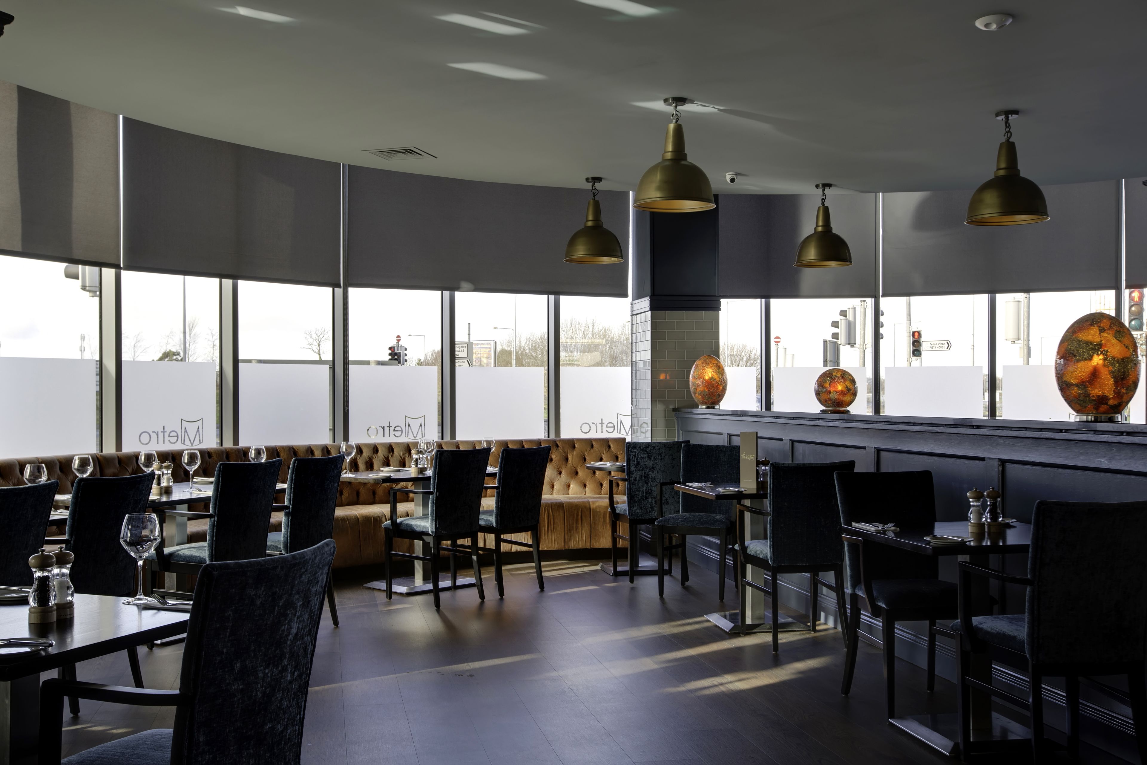 A modern restaurant with high ceilings, large windows, and a mix of seating arrangements including tables and booths.