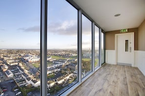 Habitación de hotel de gran altura con amplios ventanales de piso a techo que ofrecen vistas a la ciudad.