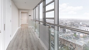 Un apartamento moderno con balcón, ventanas amplias y vista a la ciudad.