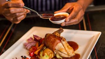A person holding a spoon with a sauce and a small bowl of sauce.