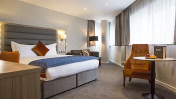 Una habitación de hotel con una cama grande, un escritorio, una silla y una mesita con fruta.