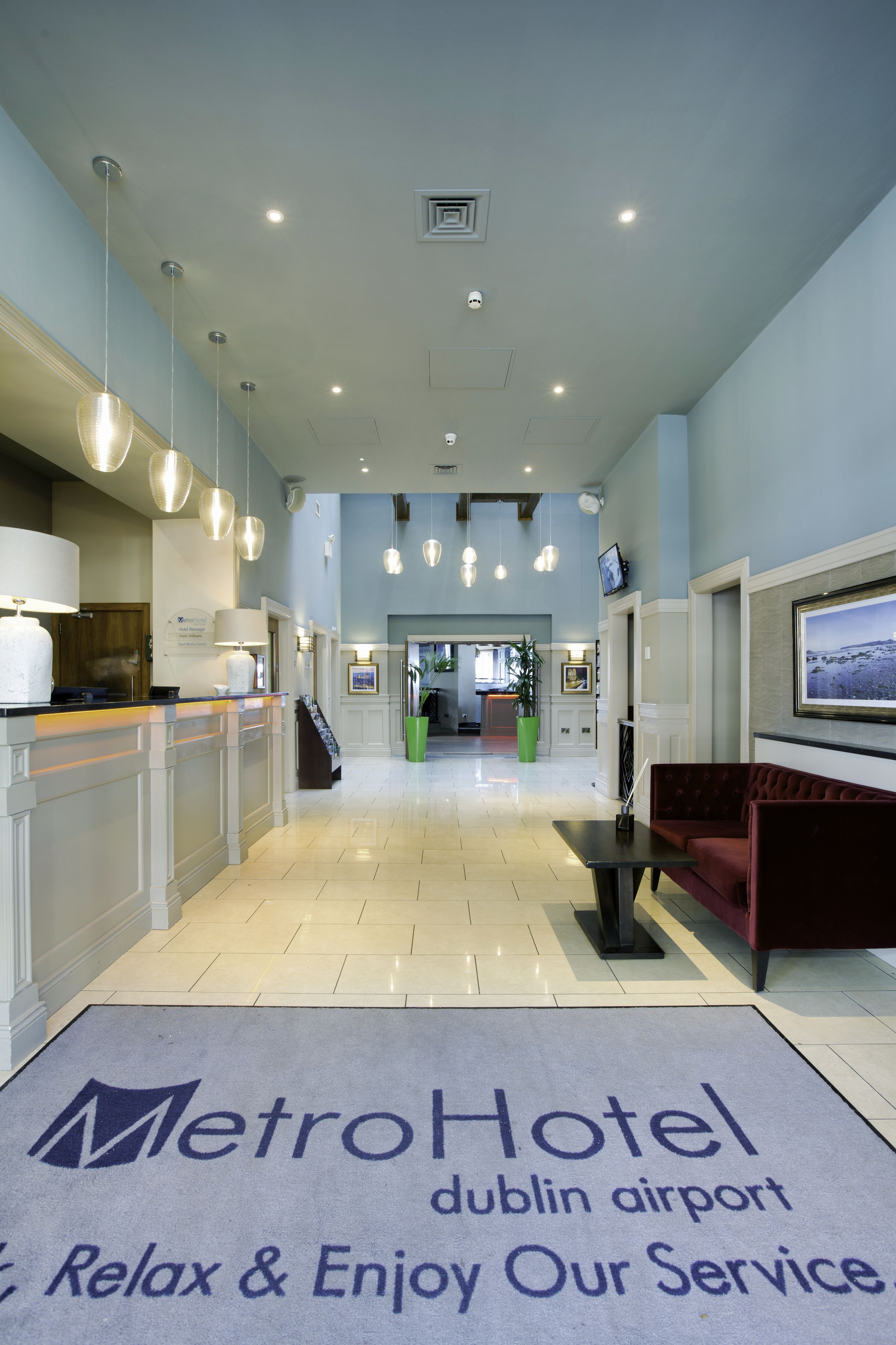 A hotel lobby with a reception desk, seating area, and a large screen displaying a scenic view.