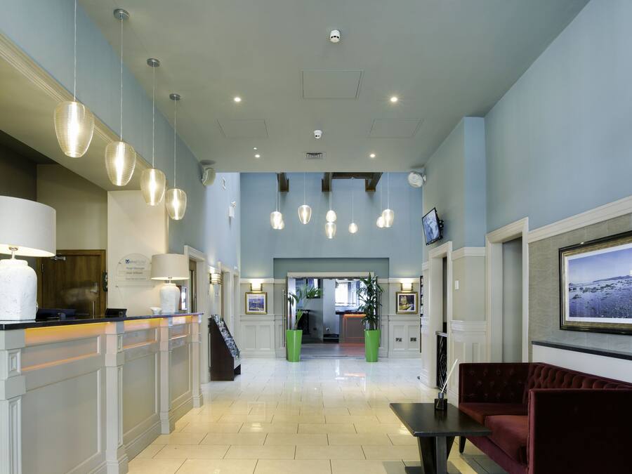 A hotel lobby with a reception desk, seating area, and a large screen displaying a scenic view.