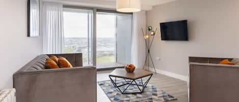 A modern living room with a sofa, a coffee table, and a TV.