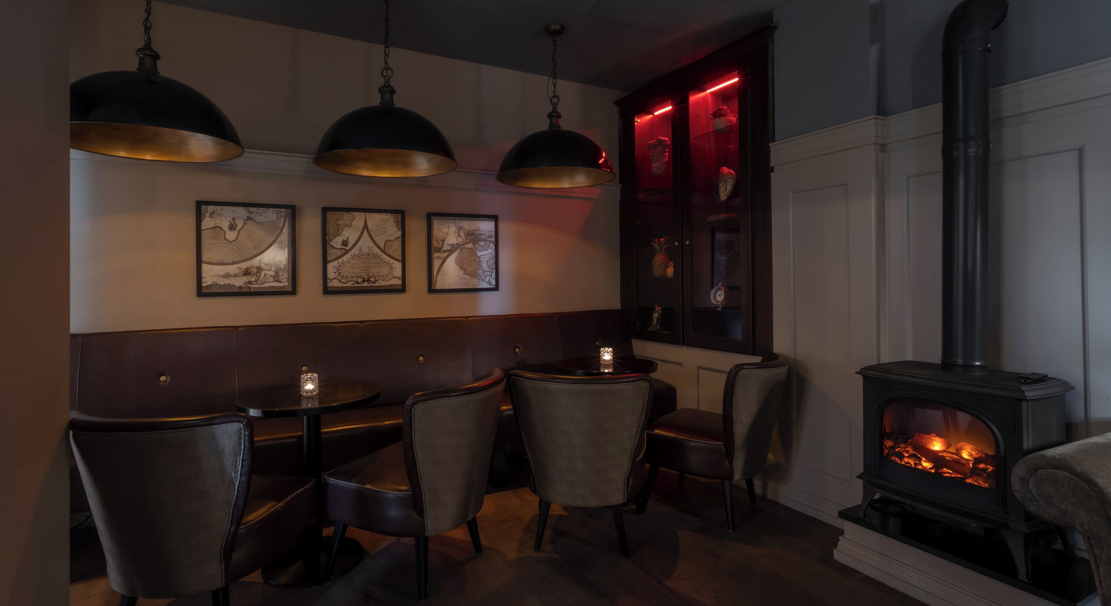 A cozy room with a fireplace, leather seating, and pendant lighting.