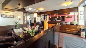 A restaurant interior with wooden furniture, a reception desk, and a clock on the wall. - Hotel Wielopole (Kraków)