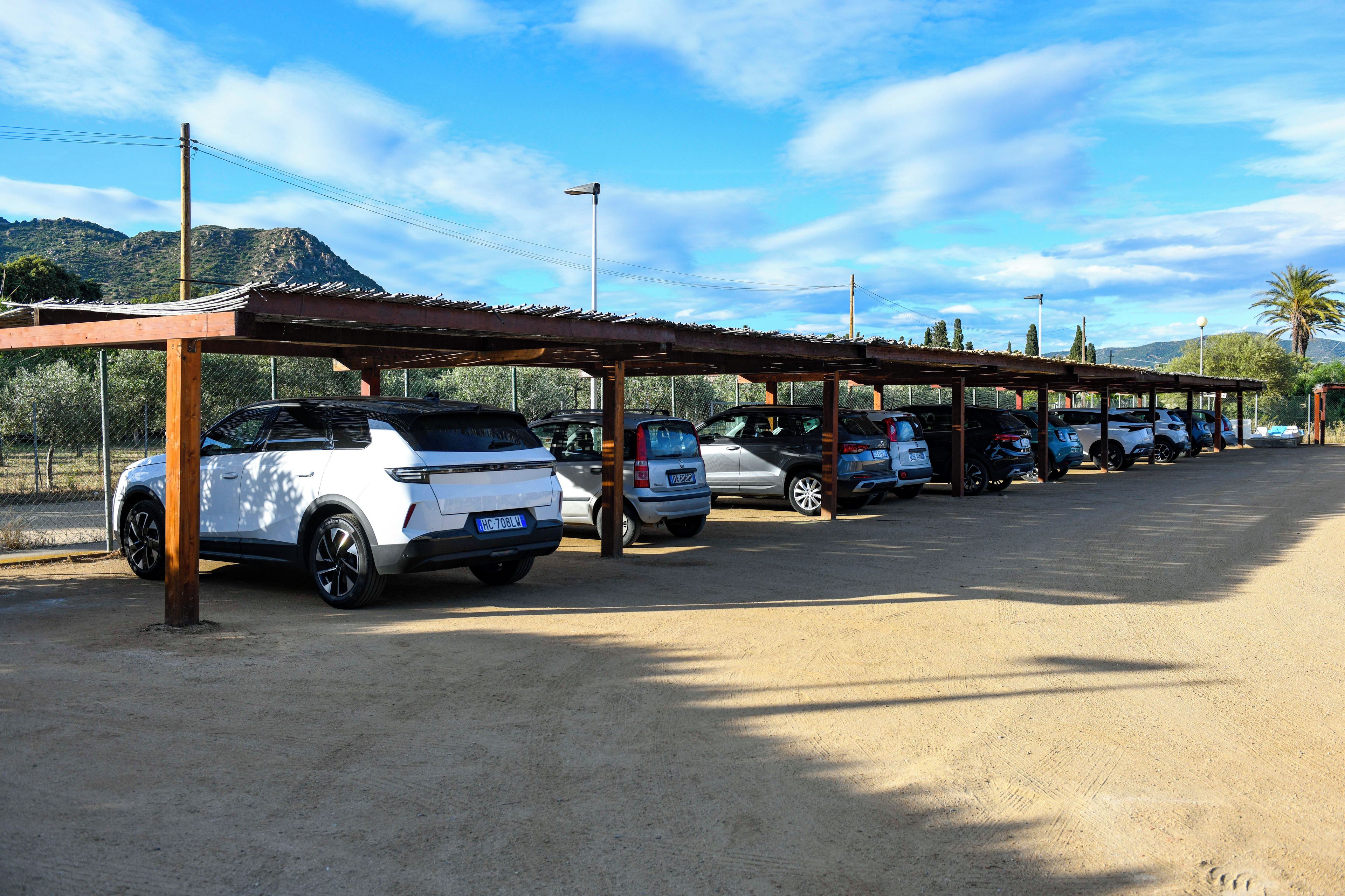 A parking area with multiple cars under a covered structure.