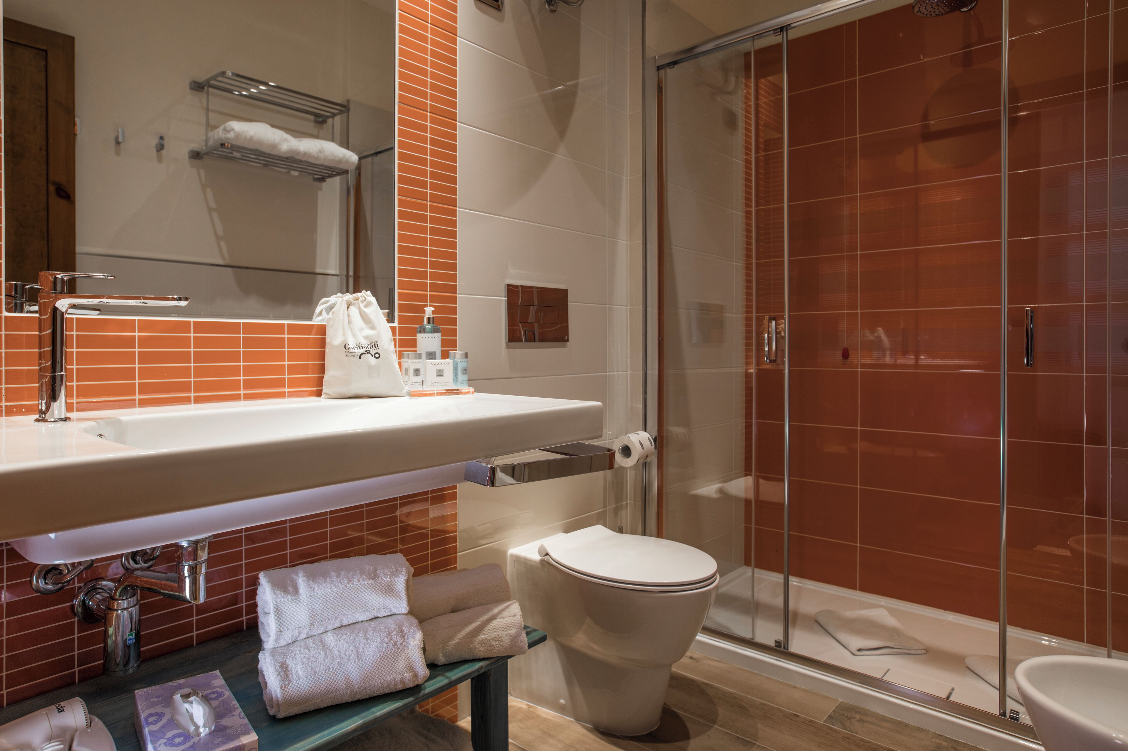 A modern bathroom with a glass-enclosed shower, a white sink with a mirror, and a toilet.