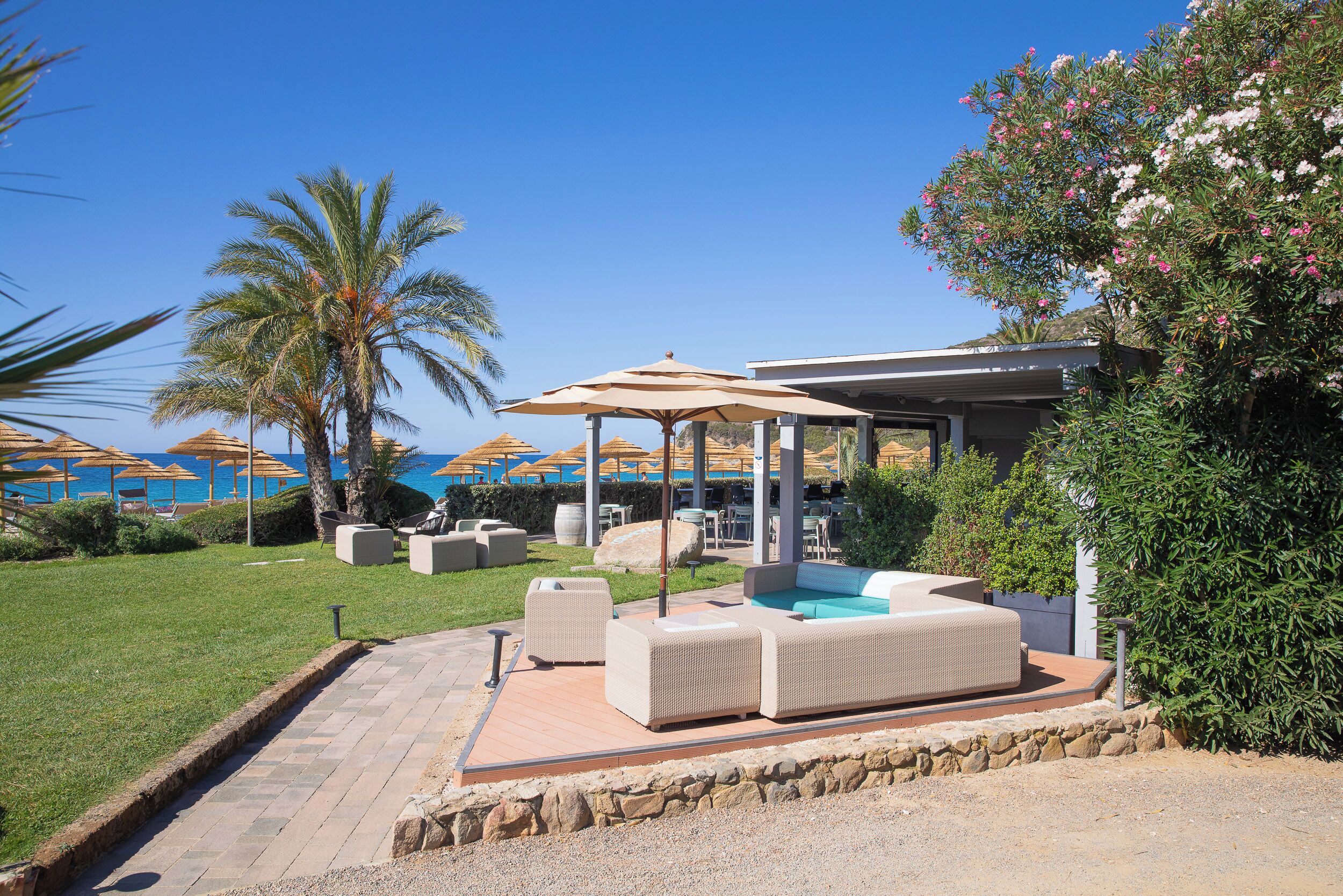 Uma área à beira da piscina com mobiliário de exterior, um alpendre coberto e vista para o mar.