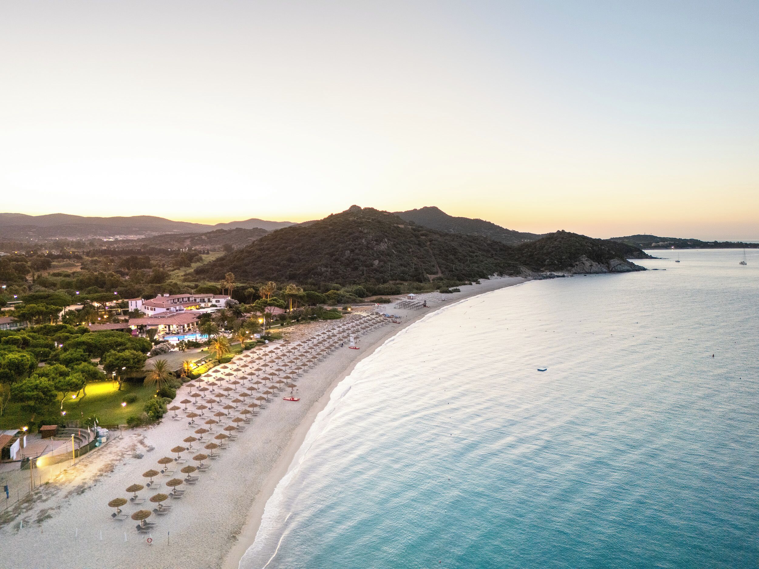 A coastal hotel with a beach view, multiple umbrellas, and a pool area.