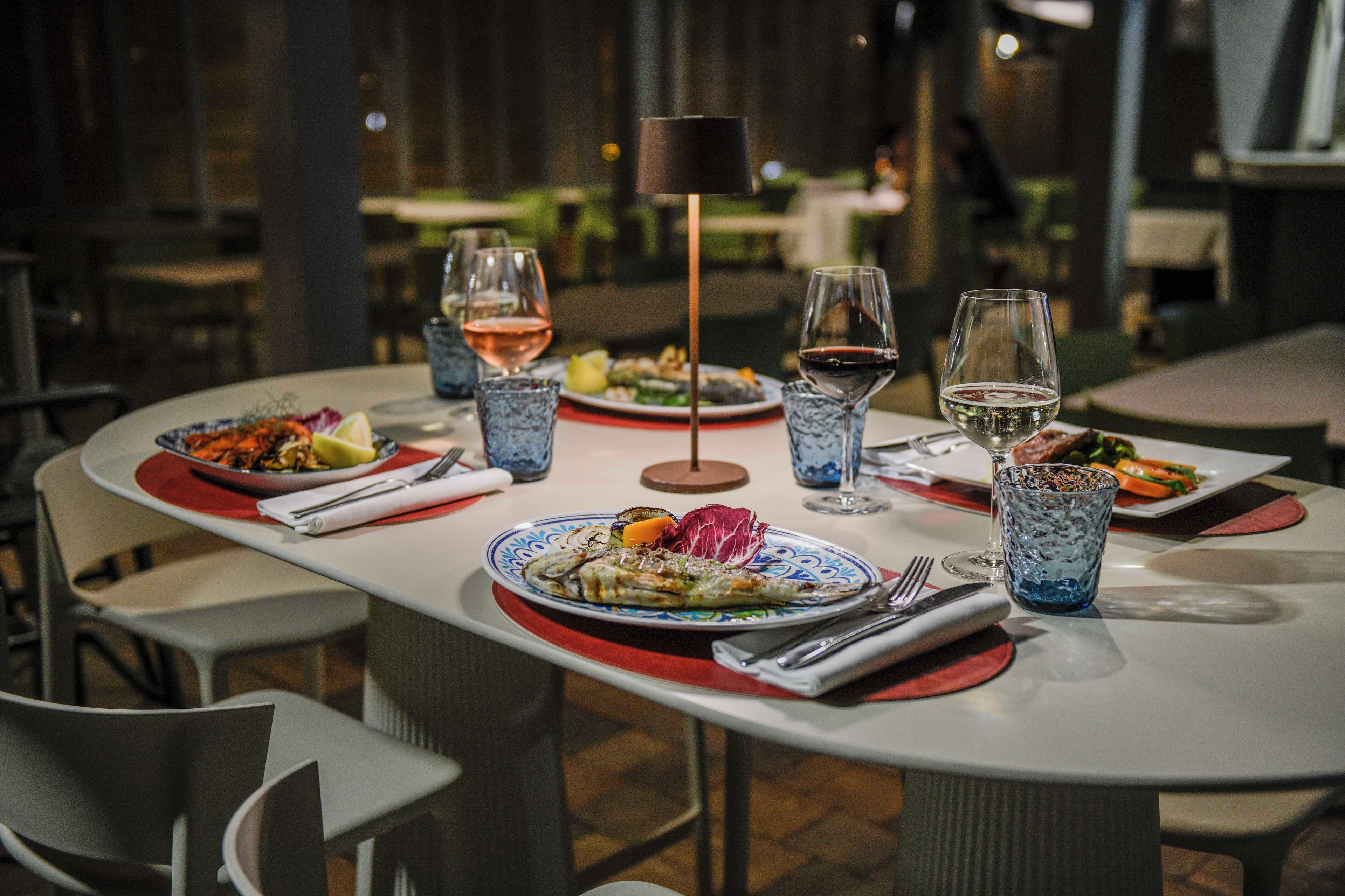 A dining table set with plates of food, glasses of wine, and cutlery.