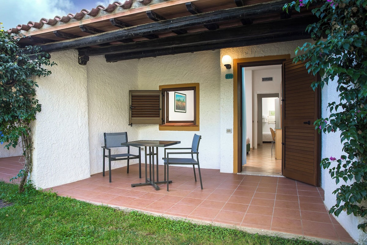 A patio with a table and chairs, a door leading to a room, and a wall-mounted picture.