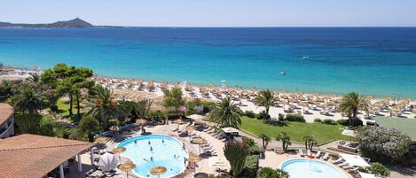 A resort with two swimming pools, beachside lounge areas, and a view of the sea.