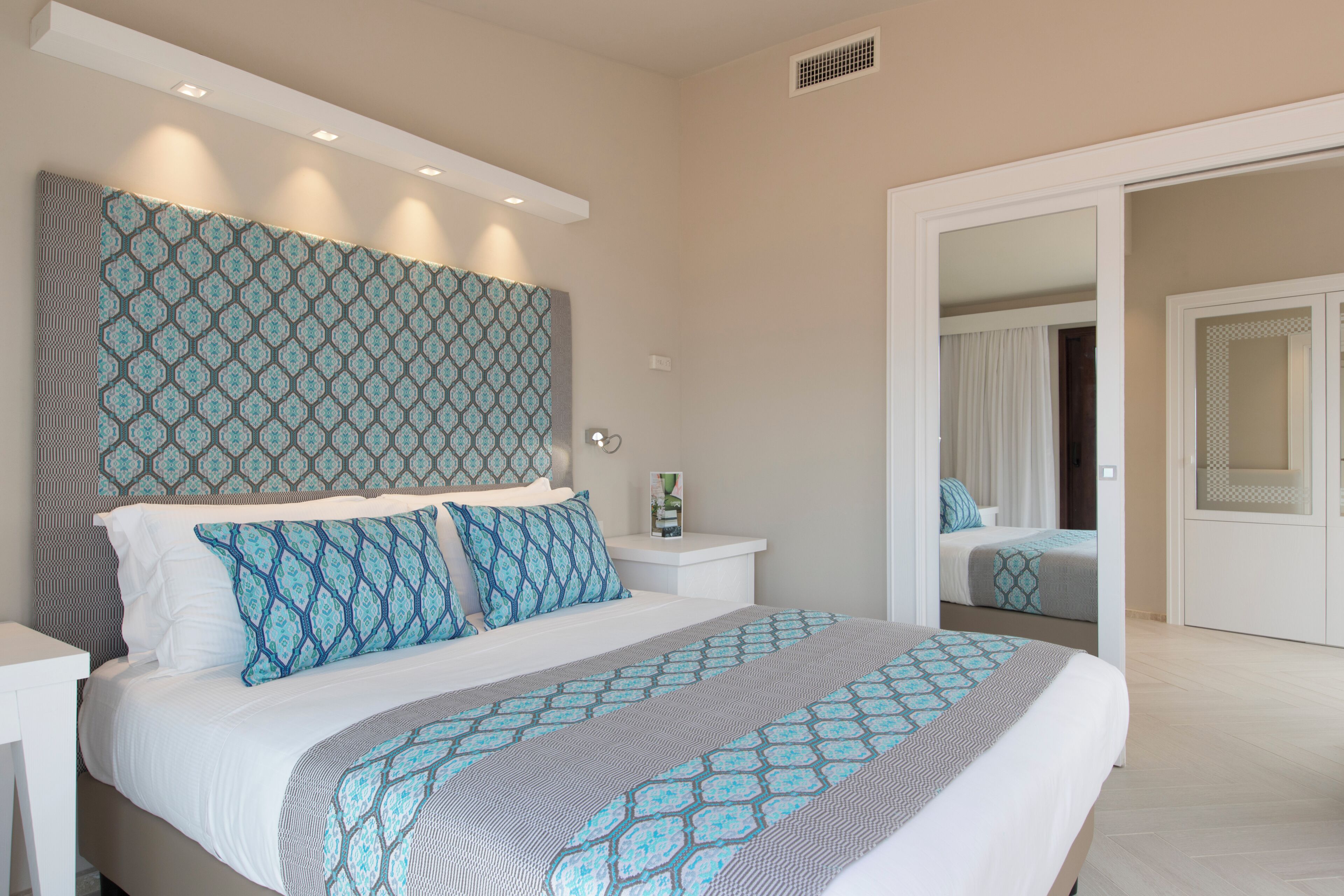 Un dormitorio moderno con una cama grande, un cabecero estampado y un vestidor.
