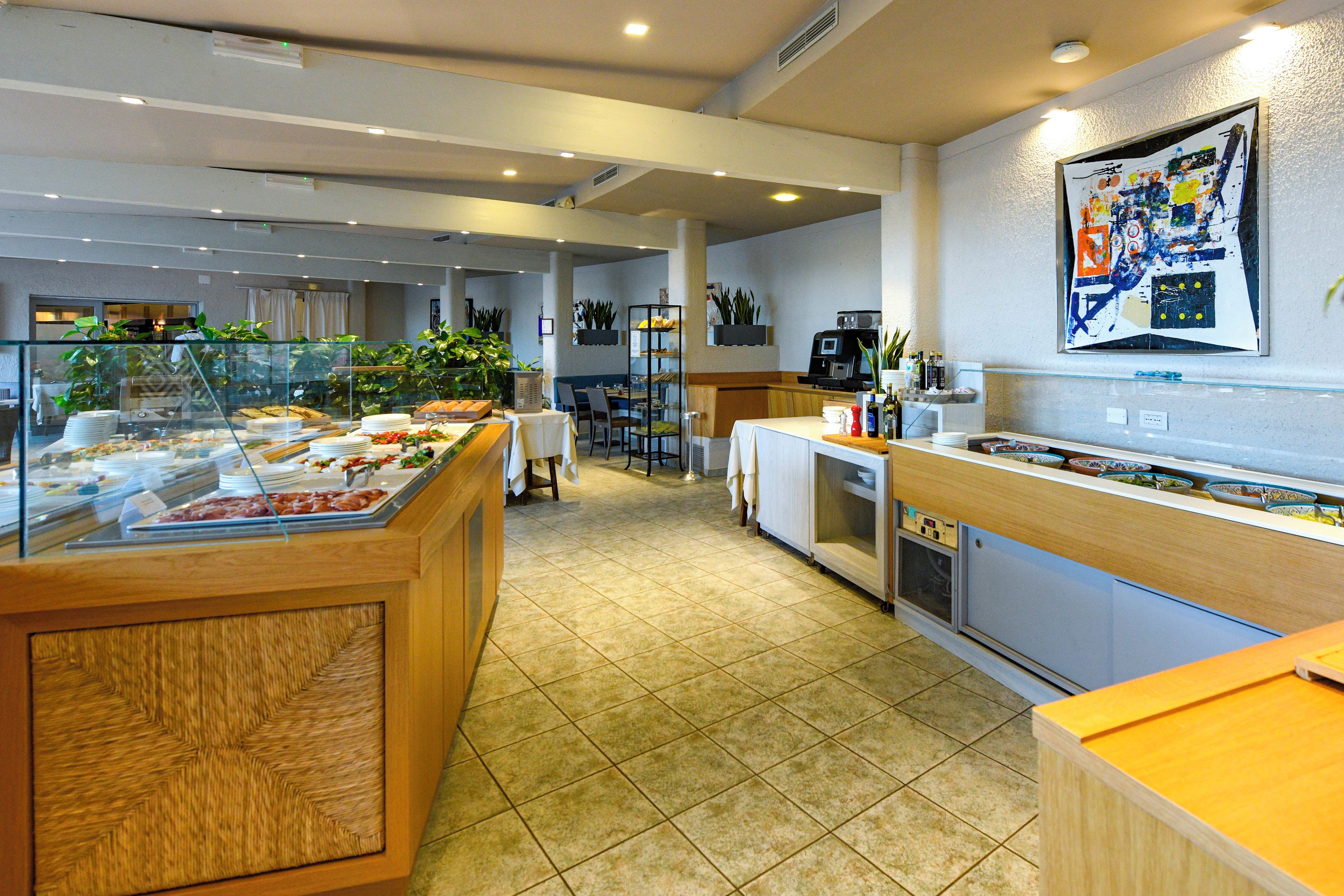 Ein Buffetbereich mit verschiedenen Speisen, einer Kaffeestation und einer Sitzgelegenheit mit Tischen und Stühlen.
