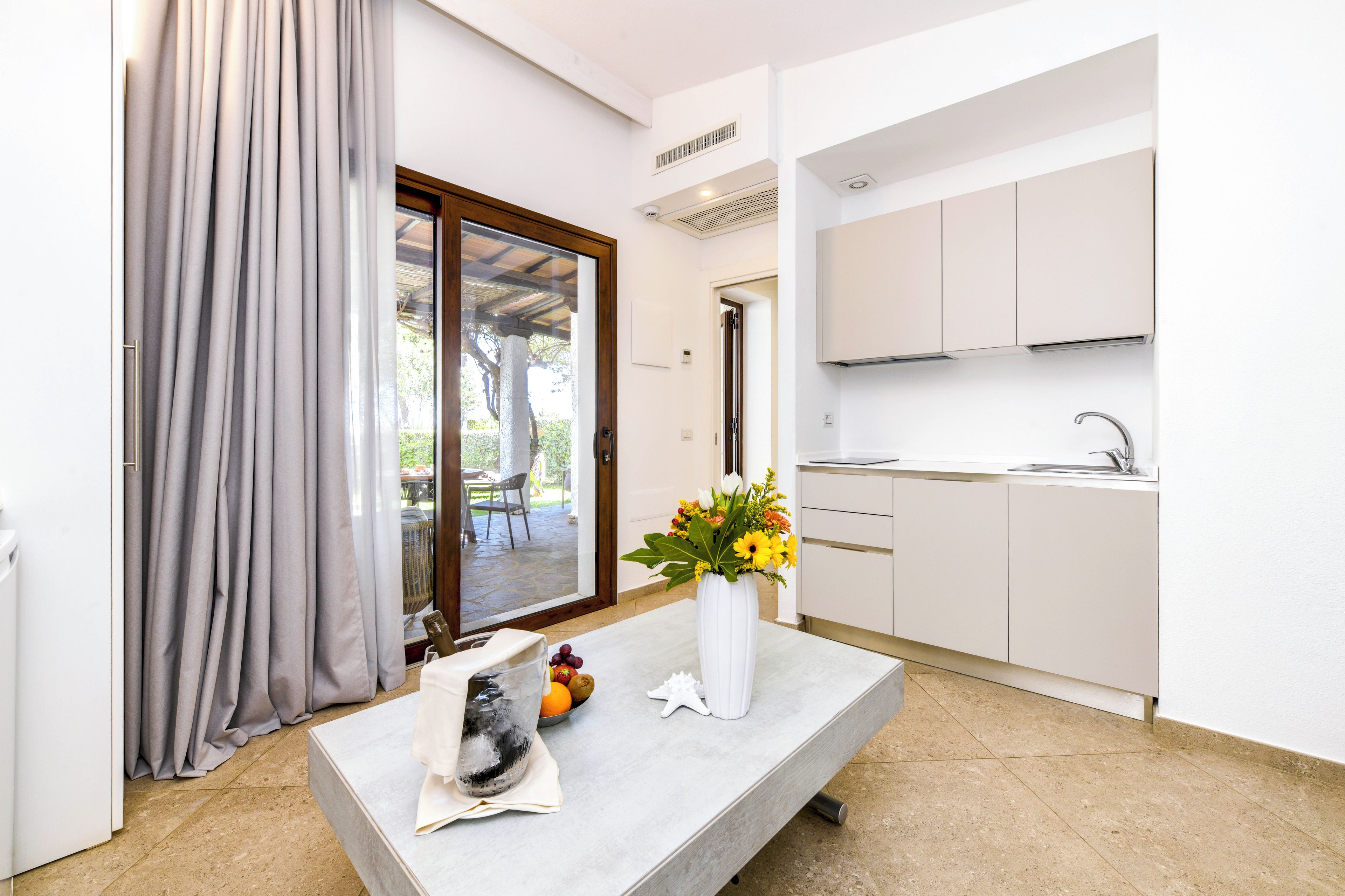 Una cocina moderna con armarios blancos, un fregadero y una zona de comedor con mesa y sillas.