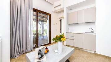Una cocina moderna con armarios blancos, un fregadero y una zona de comedor con mesa y sillas.