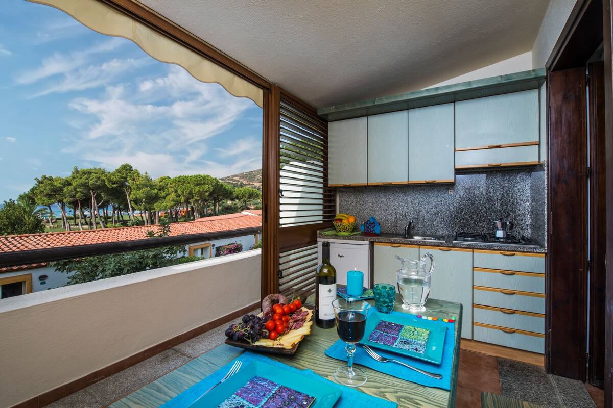 A balcony with a table set for a meal, a wine glass, and a view of the sea.