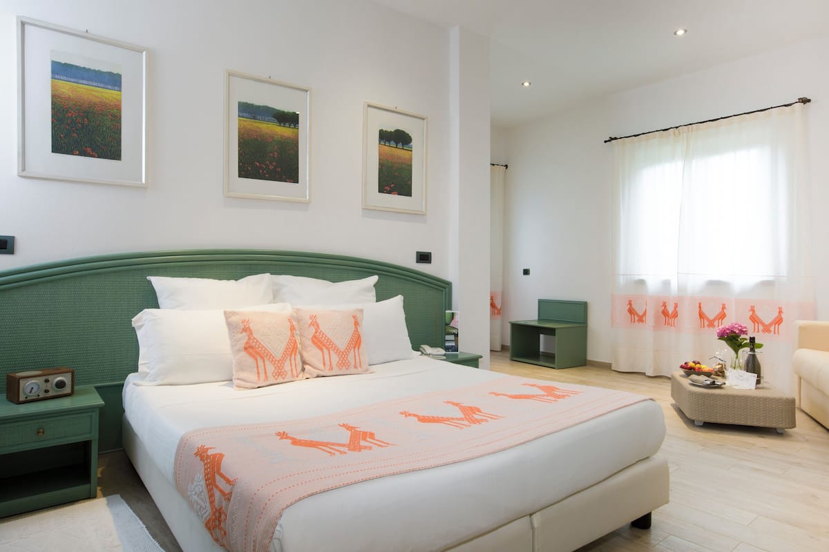 A neatly arranged bedroom with a bed, bedside tables, a chair, and artwork on the walls.