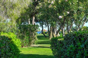 A well-maintained garden pathway leading to a seating area with a view of the sea. - Cormoran Resort Villasimius (Villasimius)
