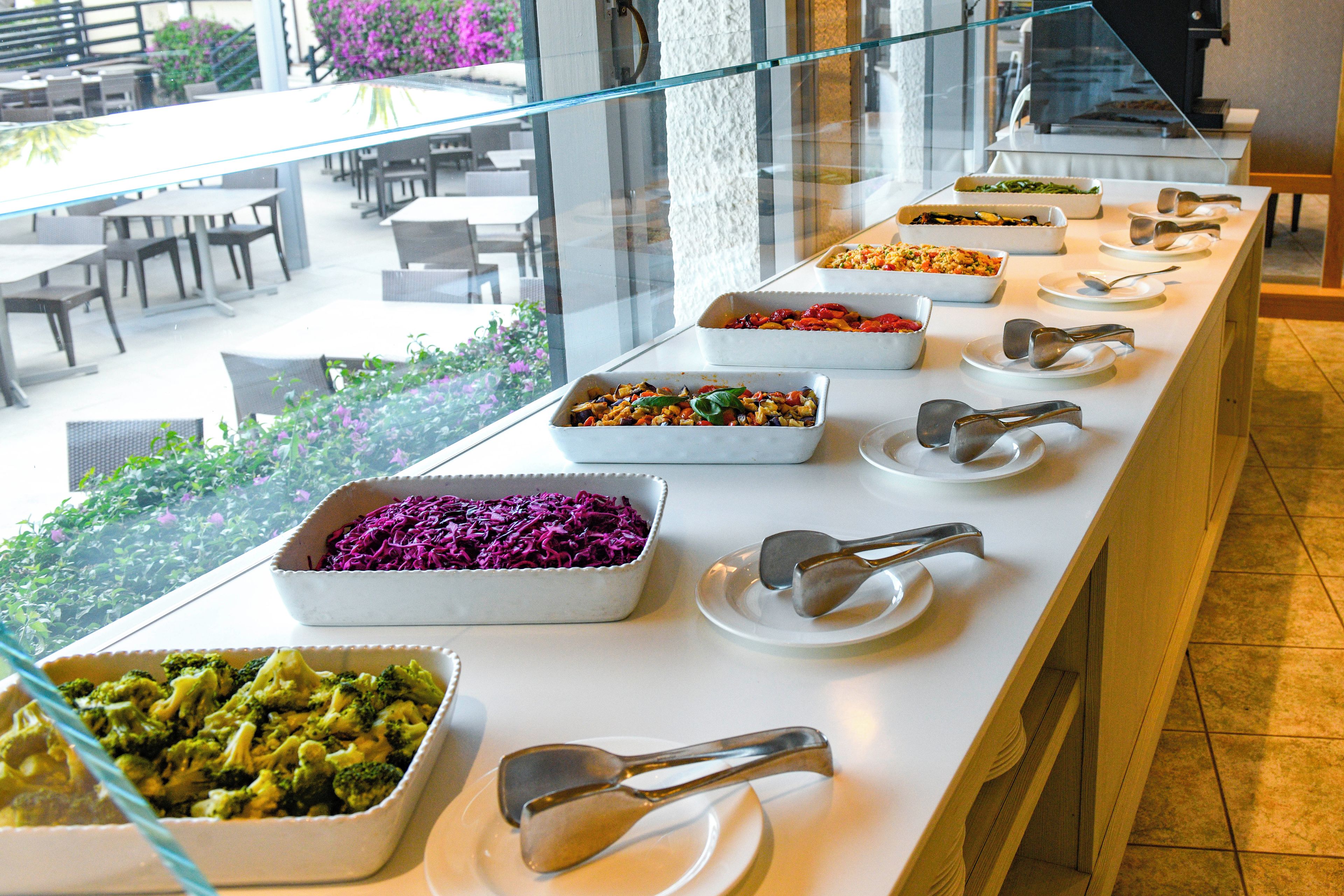 Una barra de buffet con diferentes platos y utensilios de servicio.