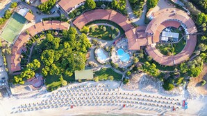 An aerial view of a resort with a beach, swimming pools, and a tennis court. - Cormoran Resort Villasimius (Villasimius)