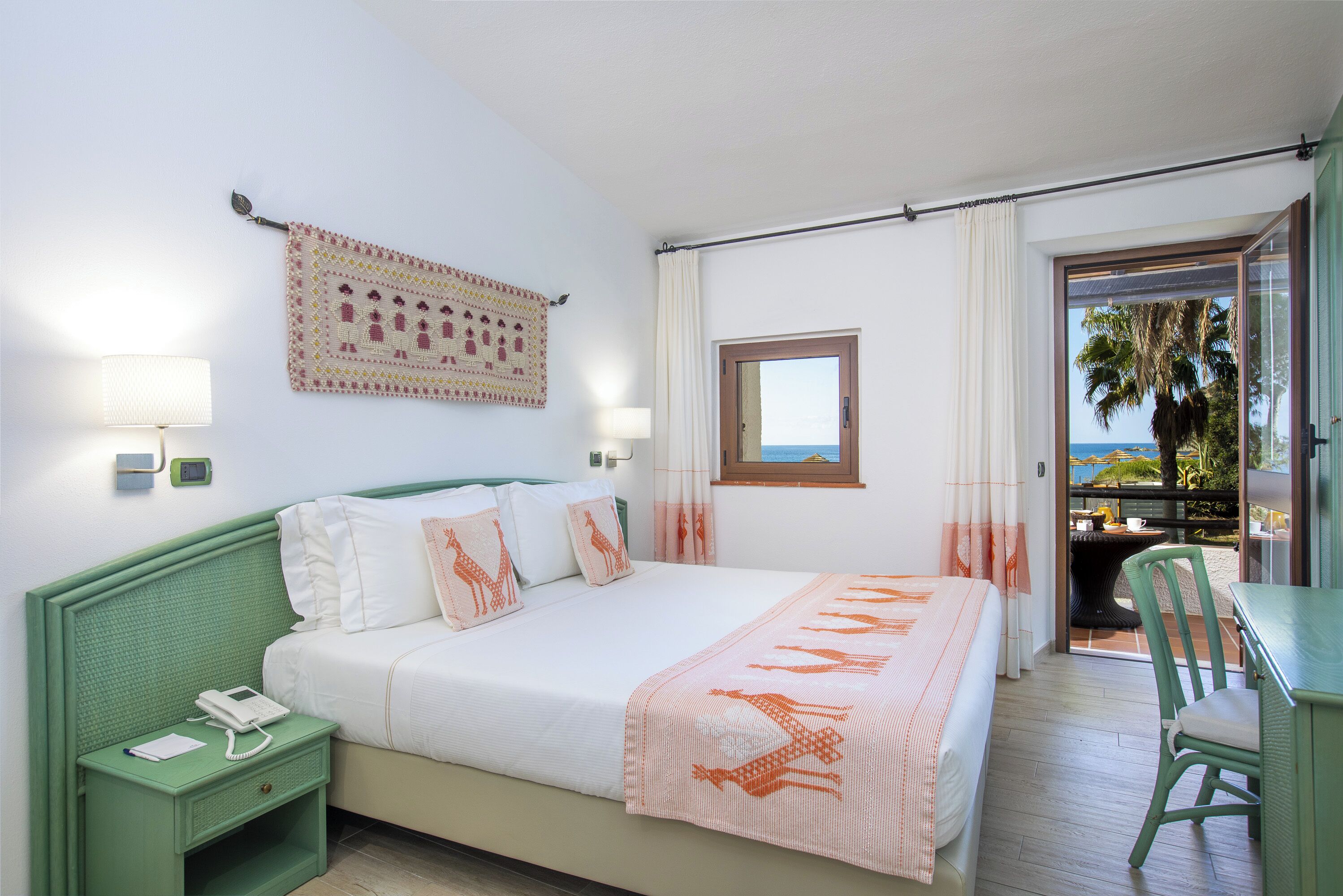 Una camera da letto con un letto, un comodino con il telefono, un elemento decorativo a parete e vista sull'esterno.
