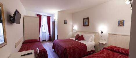 Une chambre d’hôtel avec deux lits, un bureau, une chaise, une télévision et une fenêtre avec des rideaux.