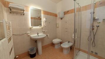 A bathroom with a sink, toilet, bidet, and a glass-enclosed shower.