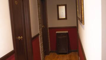 A narrow hallway with wooden flooring, red walls, and a small cabinet.