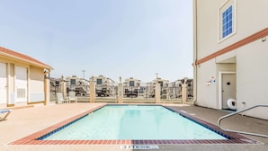 A swimming pool with a 3 FT no diving sign, surrounded by a fence, and adjacent to a building with a door and window. - Super 8 by Wyndham Alvarado (Alvarado)