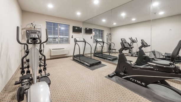 A gym with treadmills, elliptical machines, and a rowing machine. - Super 8 by Wyndham Alvarado (Alvarado)
