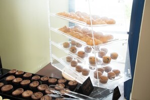A bakery display case with multiple shelves of pastries and muffins.