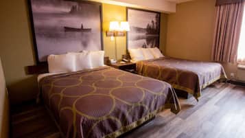 Habitación de hotel con dos camas, una mesita de noche, una lámpara y obras de arte en las paredes.