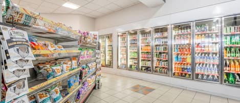 Un rayon d’épicerie où les étagères sont remplies de collations et une section réfrigérée propose diverses boissons.