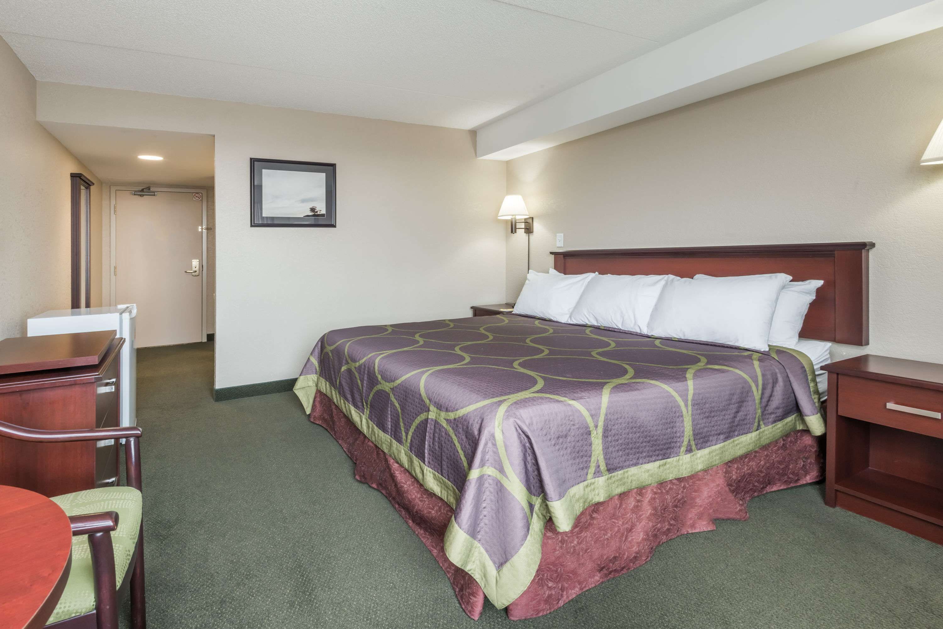 Una habitación de hotel con cama, escritorio, silla y mesita de noche.