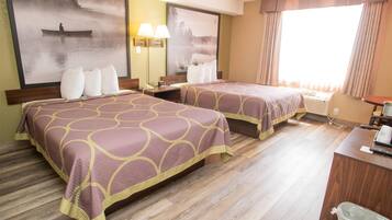 A hotel room with two beds, a desk, a chair, a trash bin, and a large window with curtains.