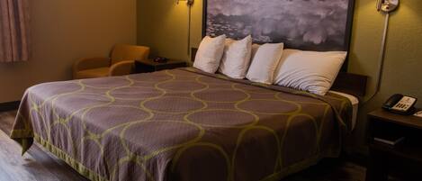 A hotel room with a large bed, two bedside lamps, a chair, and a painting on the wall.