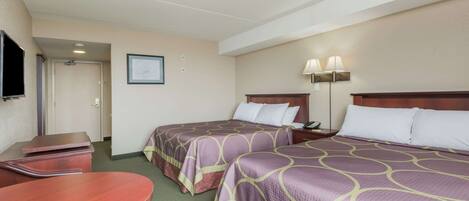 Habitación de hotel con dos camas, un escritorio, un televisor y un cuadro en la pared.