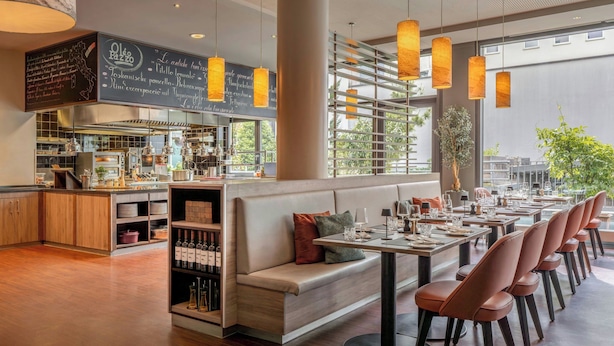 Un interior de restaurante moderno con una barra larga, zona de asientos y un menú en la pizarra.