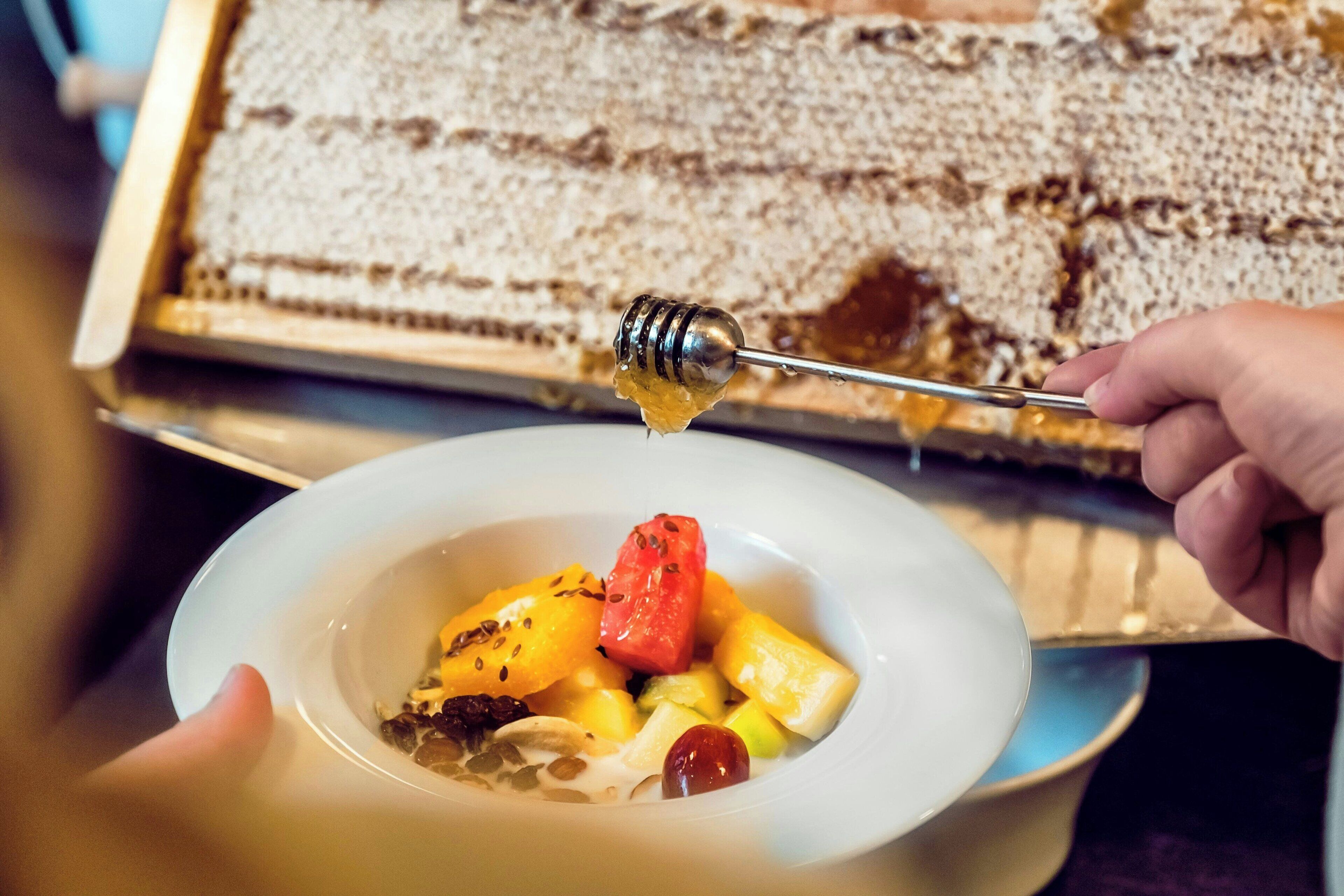 A bowl of fruit salad with a honey dipper.